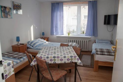 a small room with a table and two beds at APARTAMENT i pokoje Aura Dom Wczasowy in Darlowko