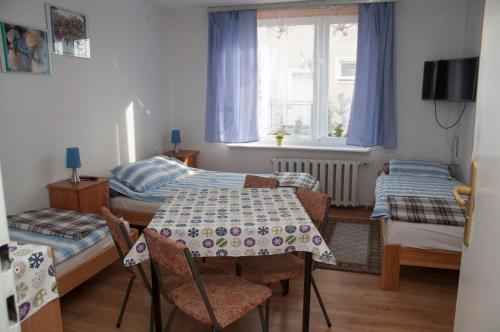 mały pokój ze stołem i 2 łóżkami w obiekcie APARTAMENT i pokoje Aura Dom Wczasowy w Darłówku