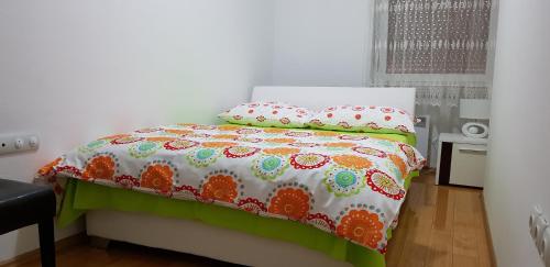 a bed with an orange and white comforter and pillows at Apartment MA in Banja Luka