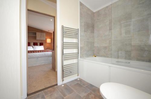 a bathroom with a bath tub and a bedroom at Victory Greenland in Amotherby