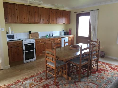 cocina con mesa de madera y armarios de madera en Shieling Holidays Mull, en Craignure