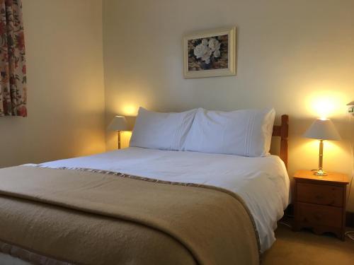 a bedroom with a bed with white sheets and two lamps at Shieling Holidays Mull in Craignure