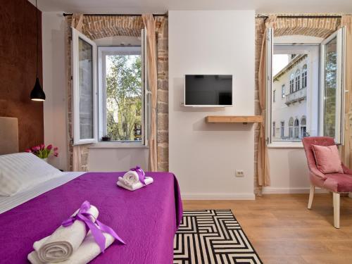 a bedroom with a purple bed and a chair and windows at Luxury room Colonna 4*, center in Zadar