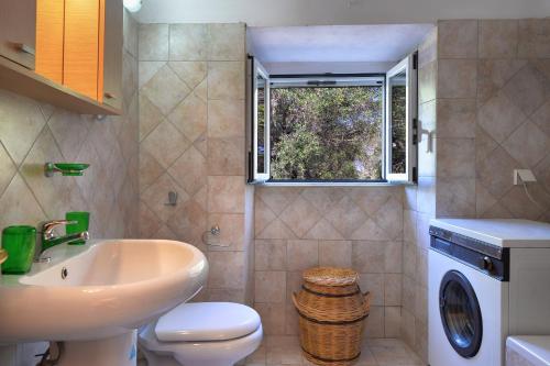 bagno con lavandino, servizi igienici e finestra di Mikroulis Residence a Mastorátika