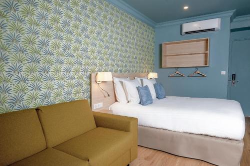 a hotel room with a bed and a couch at Hôtel Du Centre, un hôtel AMMI in Nice