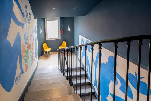 a staircase in a house with blue walls and yellow chairs at Hôtel Du Centre, un hôtel AMMI in Nice