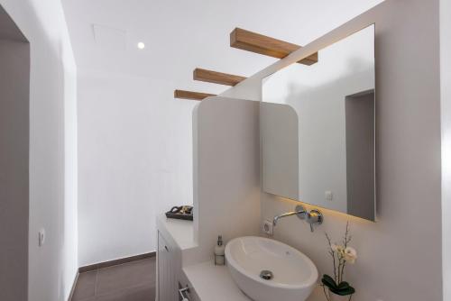a white bathroom with a sink and a mirror at Caldera's Memories in Imerovigli