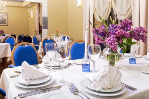 a table with white linen and purple flowers in a vase at BEST BALTIC Hotel Druskininkai Central in Druskininkai
