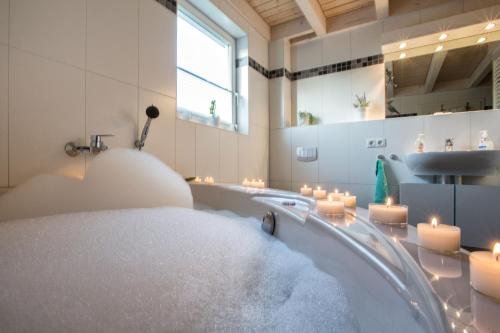 een badkamer met een bad gevuld met water en kaarsen bij Ferienhaus Nordhorn - Haus Am See in Nordhorn