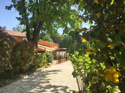 a driveway with trees and flowers in front of a house at Hotel Les Ambres in Roussillon