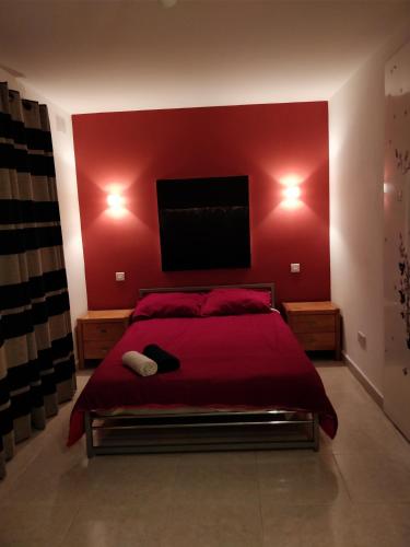 a red bedroom with a bed with a flat screen tv at Paceville Avenue Apartment in St. Julianʼs