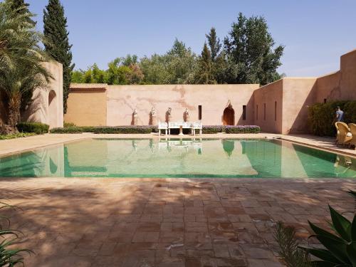 a swimming pool with two people sitting on chairs in it at Palais Claudio Bravo in Taroudant