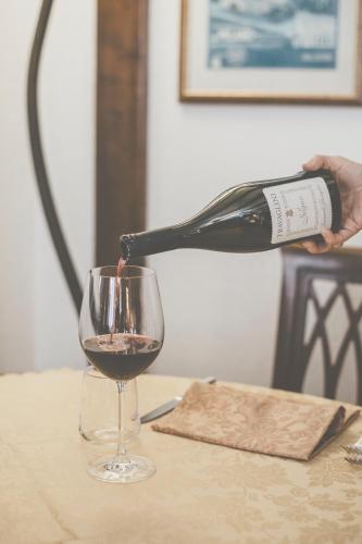 a person pouring a bottle of wine into a glass at Hotel Residence Giardini in Piode