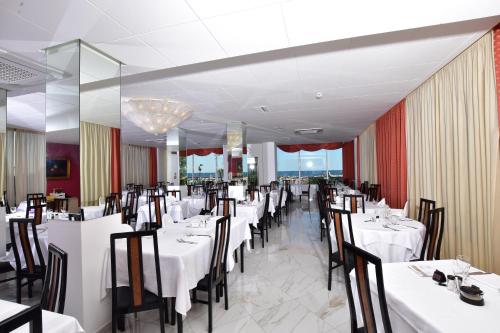 a dining room with white tables and chairs and a room with tables and chairsktop at Hotel Nord Est in Gabicce Mare