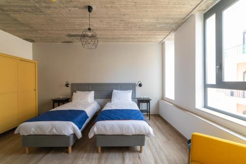 two beds in a room with two windows at Chapter 5 Hotel in Taʼ Xbiex