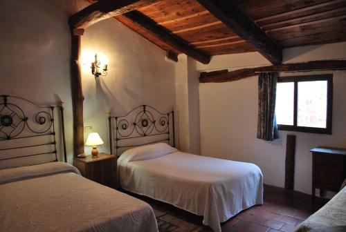 1 dormitorio con 2 camas y ventana en Fonda Del Tozal en Teruel