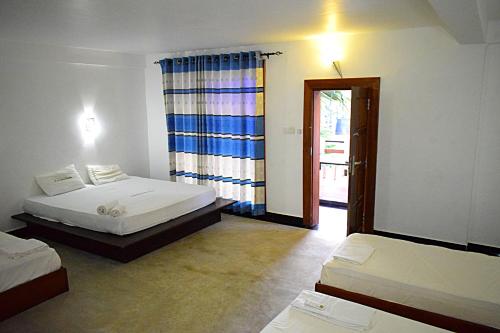a room with two beds and a door to a room with a window at Hotel Green Garden in Trincomalee