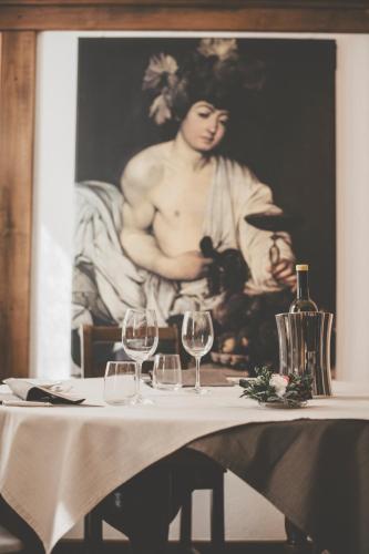 a table with wine glasses and a picture of a man at Hotel Residence Giardini in Piode