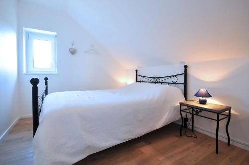 a bedroom with a white bed and a table with a lamp at Gites Chez Schangala in Thannenkirch