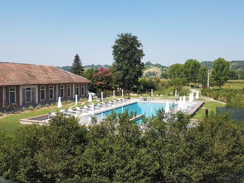 a swimming pool with white chairs and a house at Locanda Ferro UNO, Golf Città di Asti in Asti