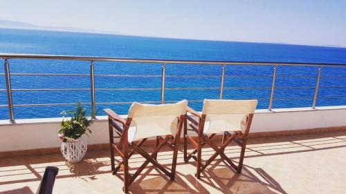 - deux chaises assises sur un balcon donnant sur l'océan dans l'établissement Villa Lori, à Qeparo