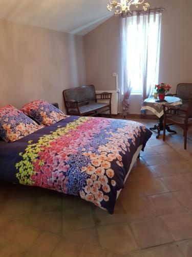 Un dormitorio con una cama con una colcha colorida. en La Pastorale, en Lagnes