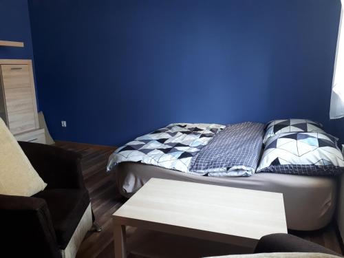 a bedroom with a bed and a blue wall at Dom pod orzechem in Spytkowice