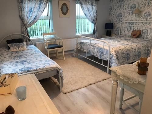 a bedroom with two beds and a chair and windows at Beau Vista in Strabane