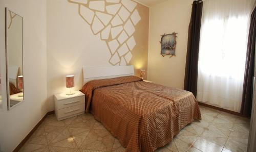 una camera da letto con un letto arancione e una finestra di La Baia Apartments by My Home Apulia a Torre Lapillo