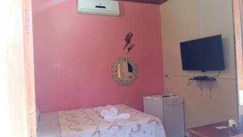 a room with a pink wall with a television and a bed at Pousada Céu Azul in Sao Jorge