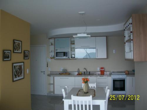 Una cocina con gabinetes blancos y una mesa y sillas. en Angra Super Luxo, en Mangaratiba