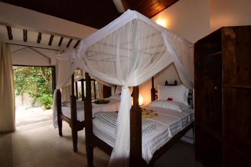 a bedroom with a canopy bed with white curtains at Tamani Villas in Matemwe