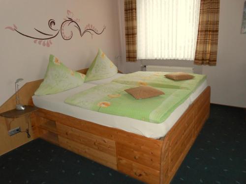 a bedroom with a wooden bed with a green comforter at Hotel Andernacher Hof in Andernach
