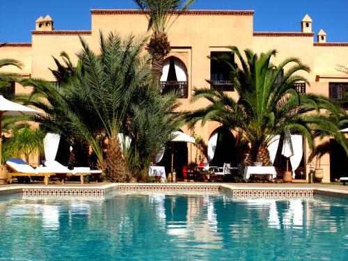 a swimming pool with palm trees in front of a building at Villa Le Perroquet Bleu in Marrakech