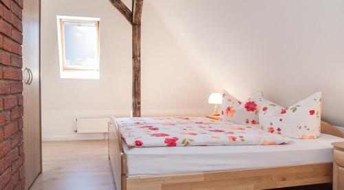 ケーニッヒスシュタイン・アン・デ・エルベにあるFerienwohnung Liliensteinblickの白いベッドルーム(赤い花のベッド付)