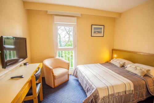 Dormitorio con cama, escritorio y TV en Hotel Le Drakkar, en Pont-Audemer