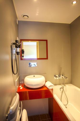 a bathroom with a sink and a bath tub at Hotel Le Drakkar in Pont-Audemer