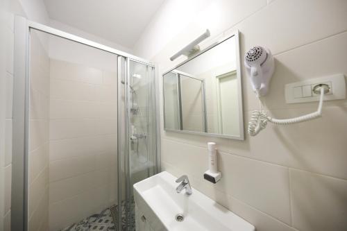 a bathroom with a sink and a shower and a mirror at Hotel Delfin in Zadar