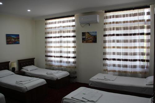 a room with three beds and windows with curtains at Hotel "GRAND WAY" in Tashkent