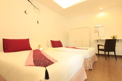 two beds in a room with a table and a chair at White Cat Hotel in Khao Lak