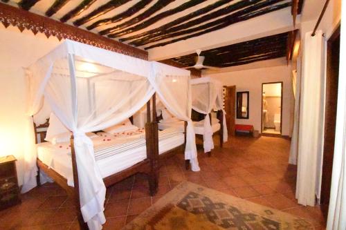 a bedroom with two beds with white drapes at Tamani Villas in Matemwe