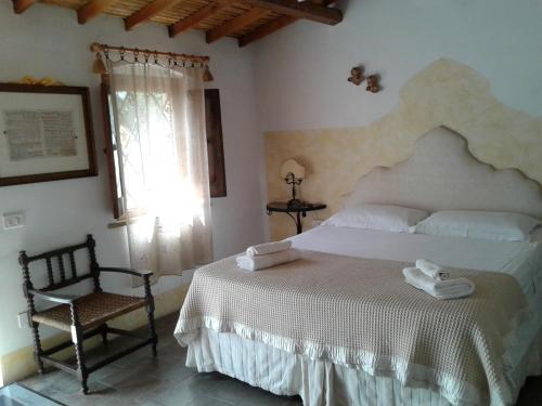 1 dormitorio con 1 cama, 1 silla y 1 ventana en L'AGRUMETO SEGRETO, en Riola Sardo