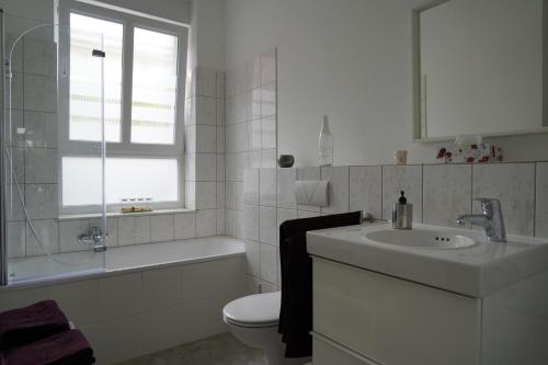 a bathroom with a sink and a toilet and a window at Altstadtwohnung mit eigenem Hauseingang in Mülheim an der Ruhr