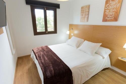 a bedroom with a white bed with a wooden headboard at Palm Friendly Holiday Home in Playa del Ingles