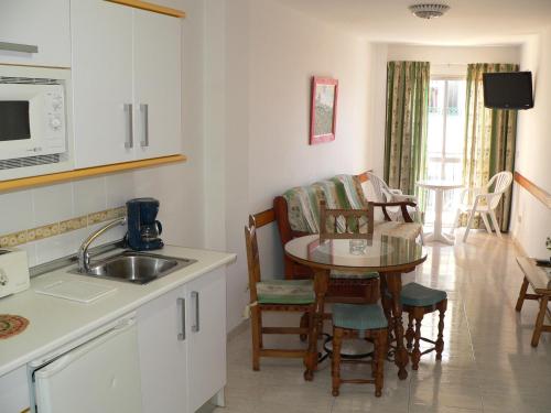 a kitchen with a sink and a table with chairs at Apartamentos Casanova in Nerja