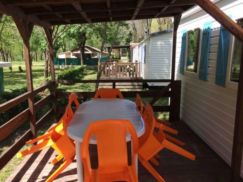 - une table et des chaises sur la terrasse couverte d'une maison dans l'établissement Camping Les Gorges de l'Hérault, à Sumène