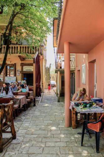 a group of people sitting at tables in an alley at Vida`s house in Virpazar