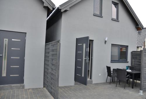 a white house with black doors and a table at Pueblo Apartamenty in Stegna