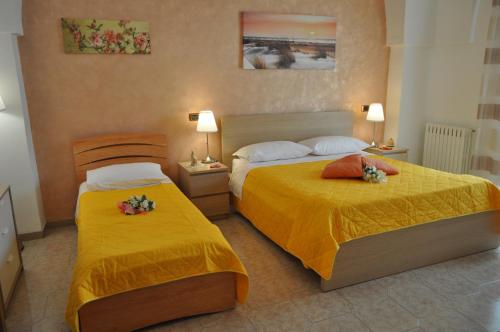 two beds in a hotel room with yellow sheets at 7 Contrade in Taranto
