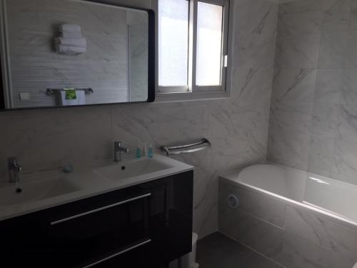 a bathroom with a sink and a tub and a mirror at Le Galion Hotel et Restaurant Canet Plage - Logis in Canet-en-Roussillon